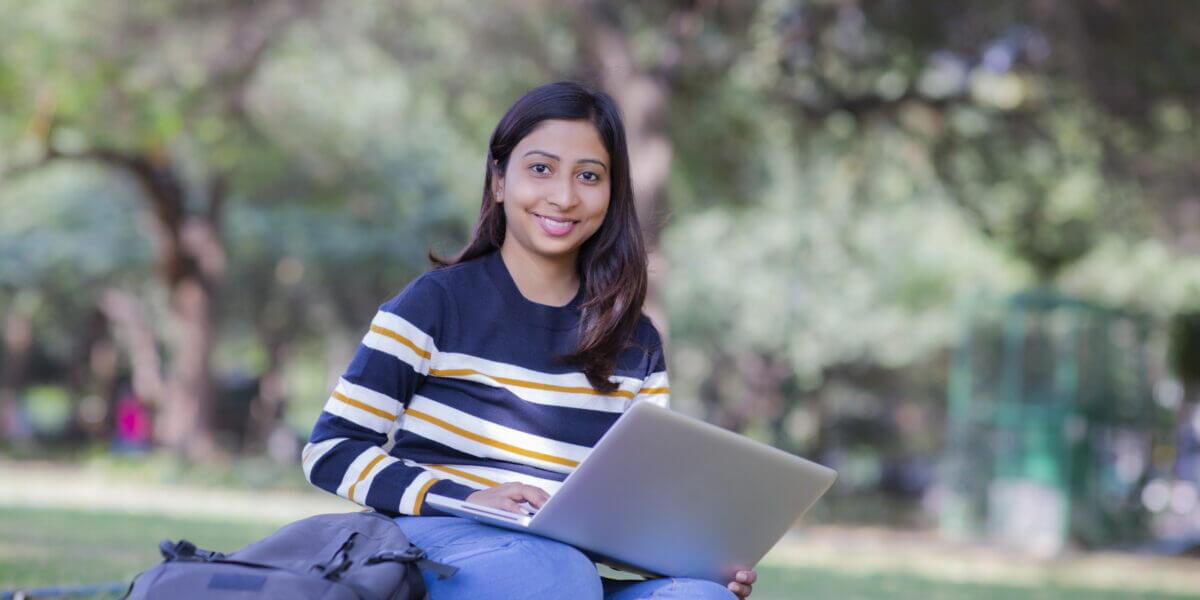 Student sitting outdoors studying on a laptop