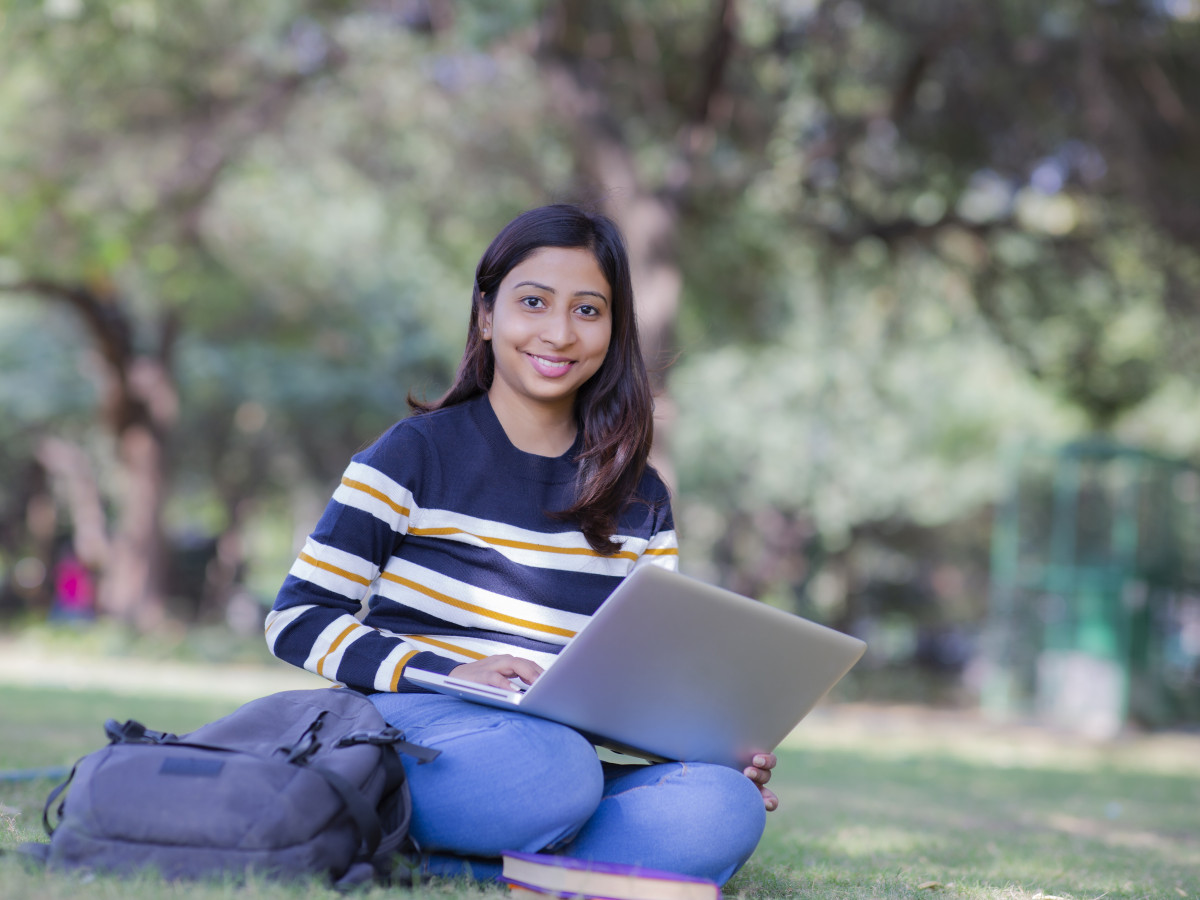 Student sitting outdoors studying on a laptop