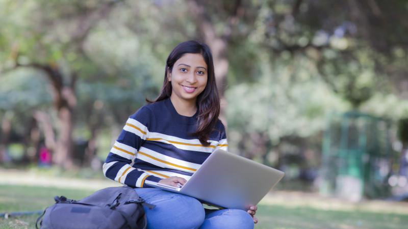 Student sitting outdoors studying on a laptop
