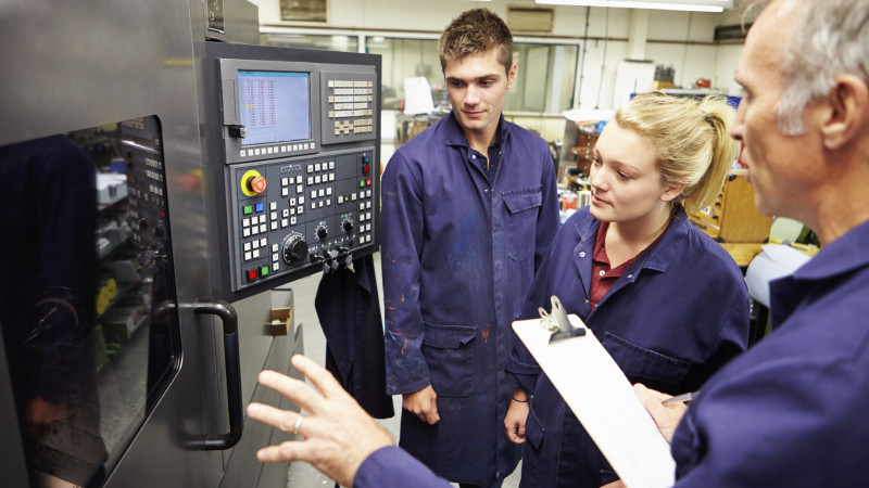 Engineer Teaching Apprentices To Use Computerized Lathe