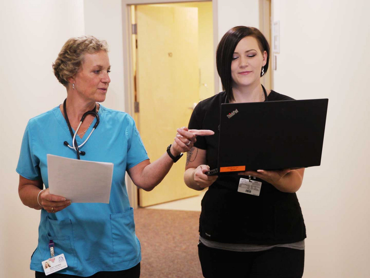 two medical assistants looking at laptop