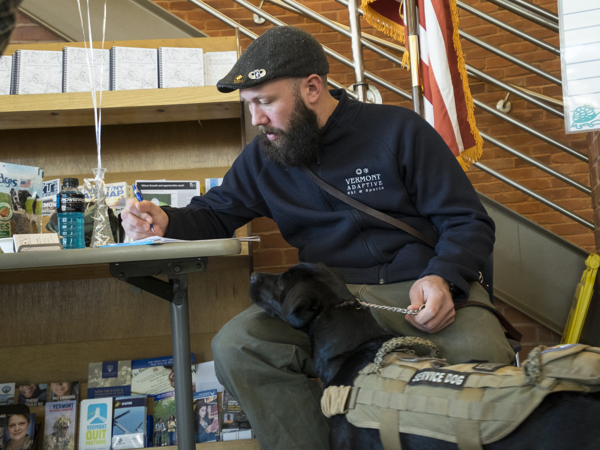 A CCV veteran alumnus and his service dog filling out paperwork at CCV-Winooski