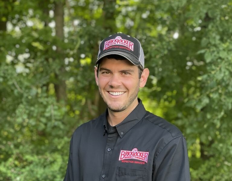 Calvin Caswell standing in front of trees wearing a BrickKicker hat and t-shirt.