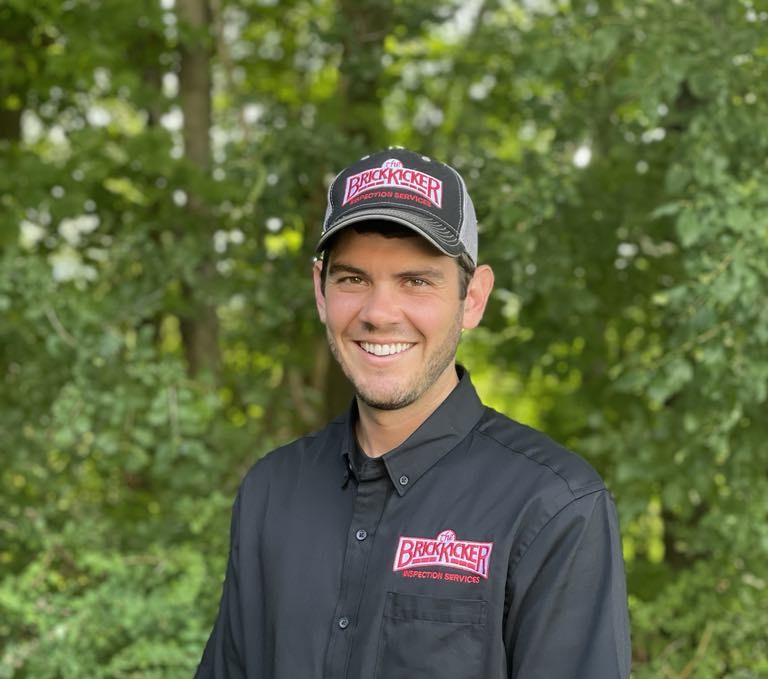 Calvin Caswell standing in front of trees wearing a BrickKicker hat and t-shirt.