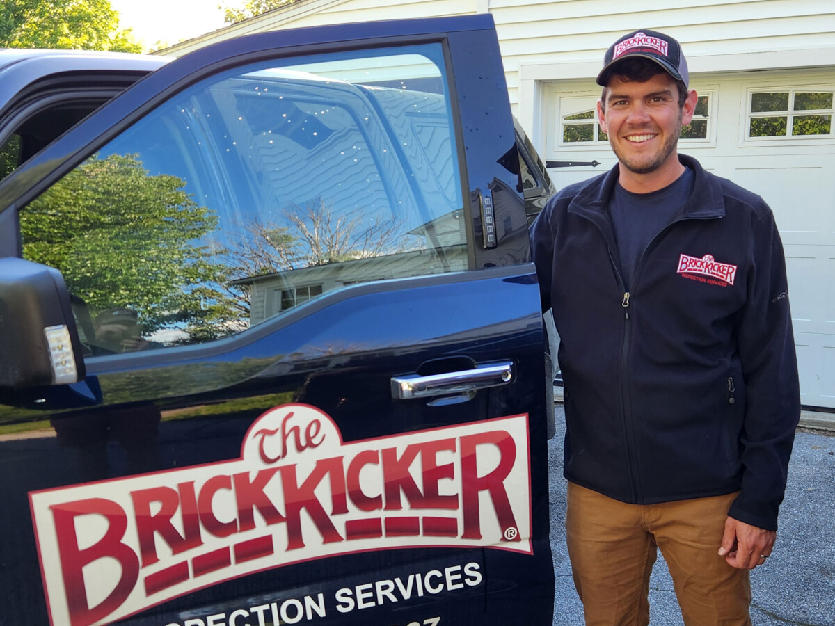 CCV alumnus Calvin Caswell opening the door of his truck, which has the BrickKicker logo on it.