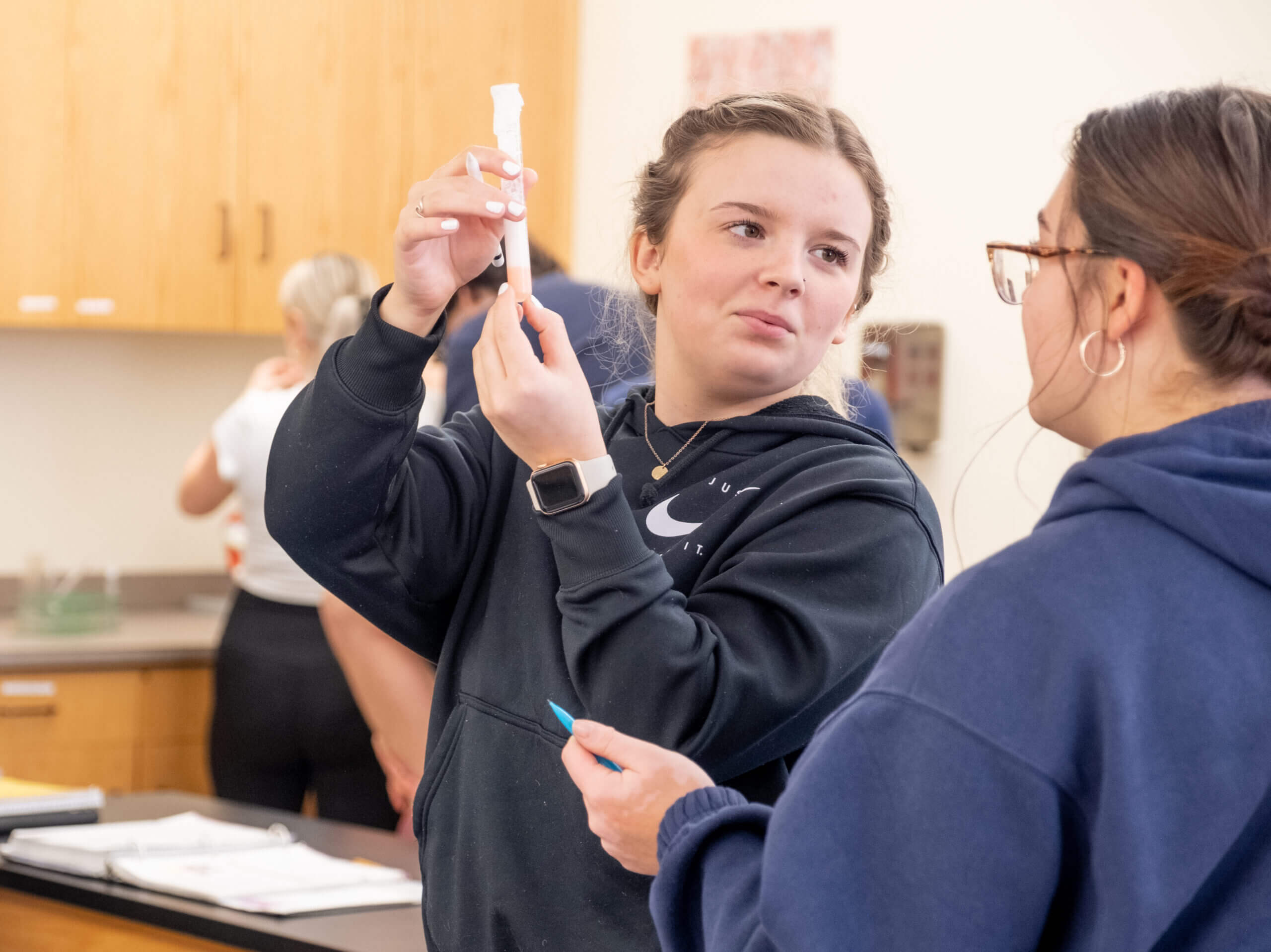 Two students in lab discussing experiment, one holding a test tube
