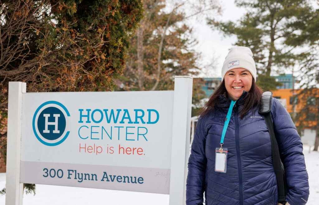 CCV alumna Megan Quigley standing next to a sign for Howard Center.
