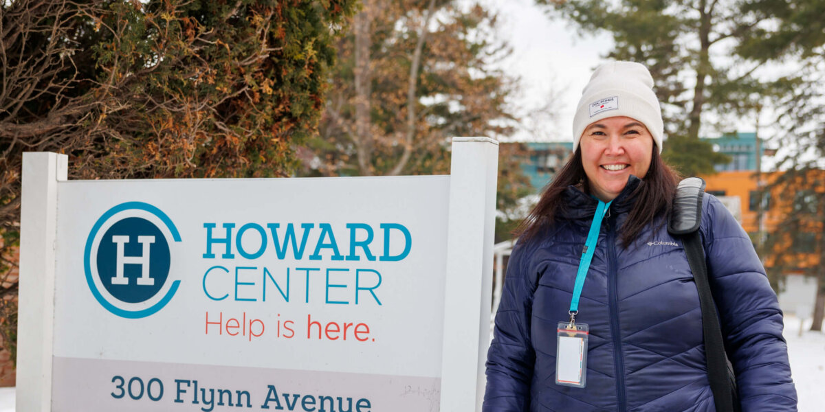 CCV alumna Megan Quigley standing next to a sign for Howard Center.