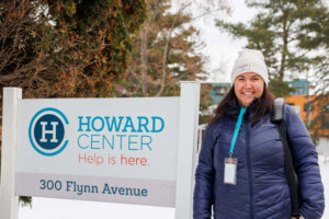 CCV alumna Megan Quigley standing next to a sign for Howard Center.