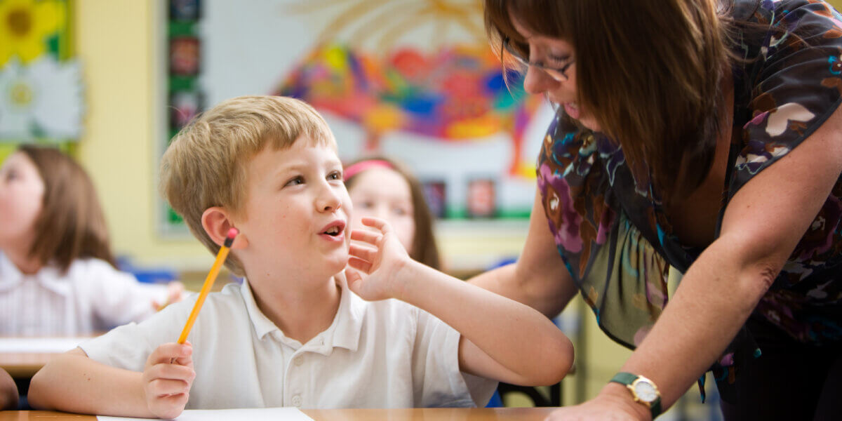 A moment of understanding from a young primary school pupil beginning to understand his subject with a little help from his teacher in the classroom.