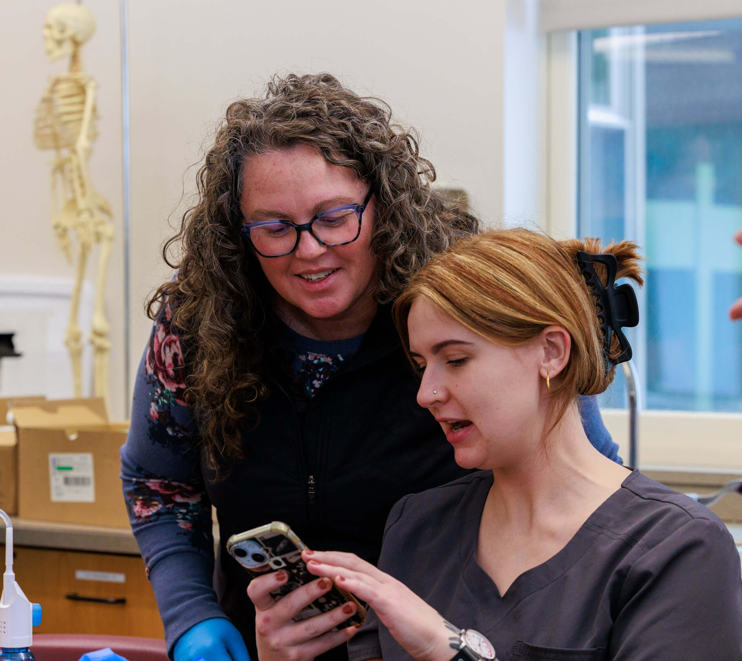 Instructor and student looking at coursework together on a phone.